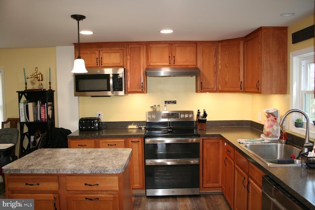 kitchen with stainless steel appliances, brown cabinets, a sink, and under cabinet range hood