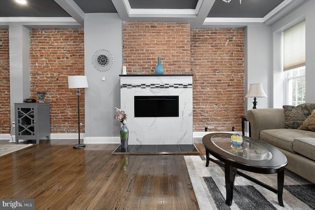 unfurnished living room with brick wall, wood-type flooring, baseboards, and crown molding