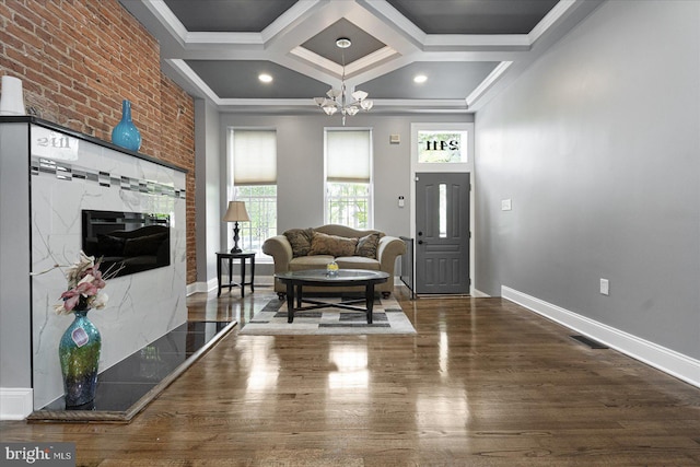 living room with baseboards, visible vents, coffered ceiling, ornamental molding, and wood finished floors