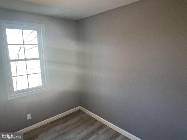 empty room featuring baseboards and dark wood-type flooring