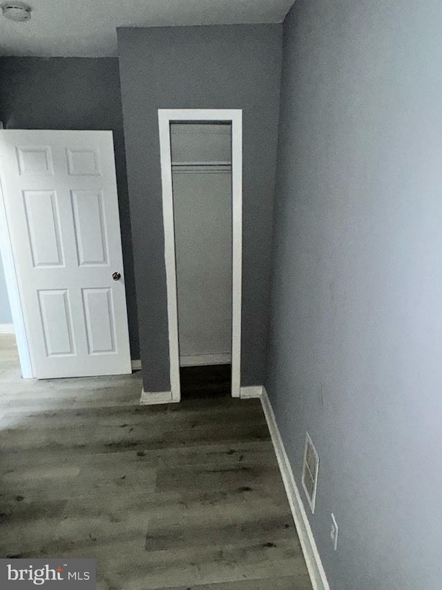 unfurnished bedroom featuring a closet, visible vents, baseboards, and wood finished floors