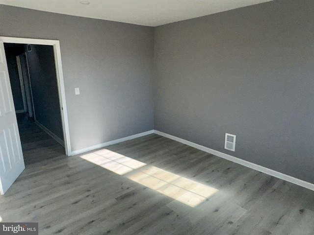 spare room featuring visible vents, baseboards, and wood finished floors