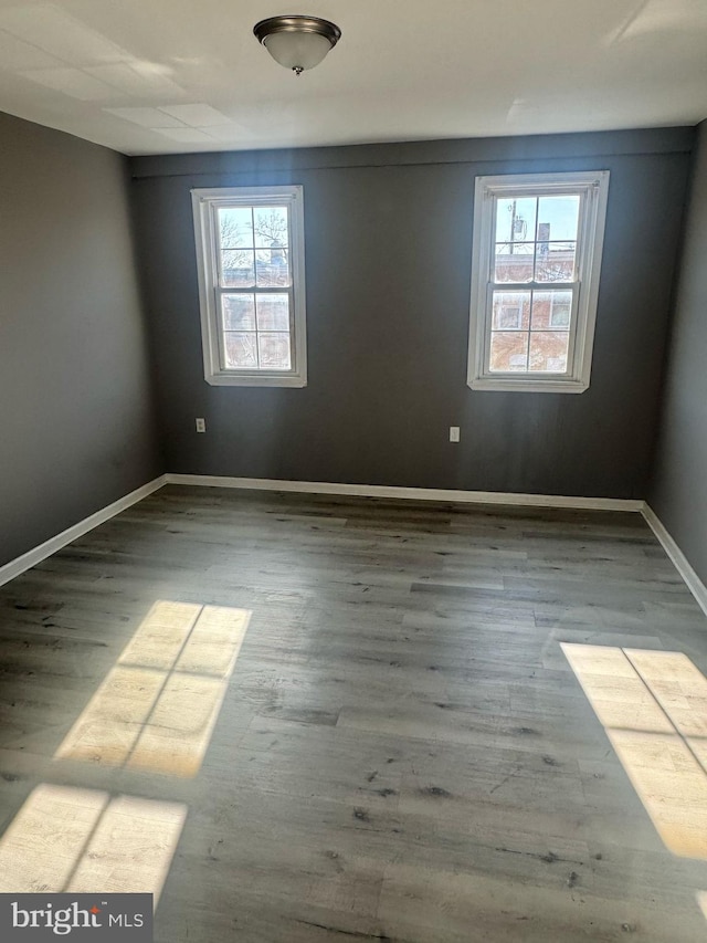 unfurnished room with baseboards and wood finished floors