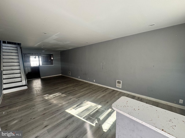 unfurnished room featuring visible vents, stairs, baseboards, and wood finished floors