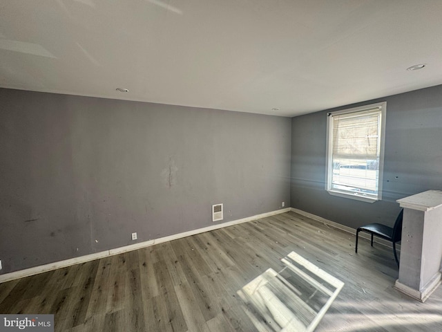 spare room featuring wood finished floors, visible vents, and baseboards