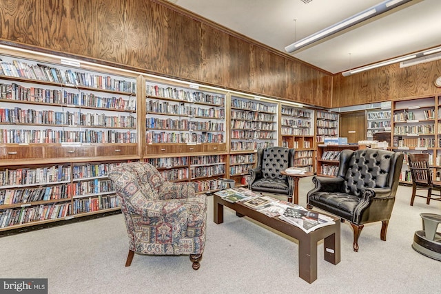 living area featuring carpet floors, bookshelves, and wood walls