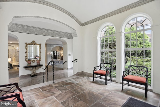 foyer entrance with lofted ceiling, baseboards, arched walkways, and crown molding