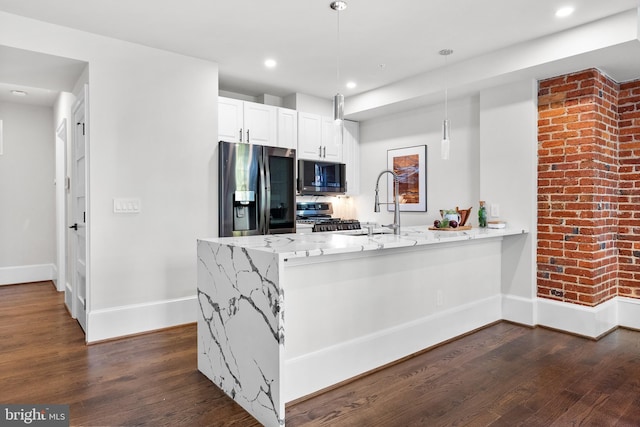 kitchen featuring light stone countertops, appliances with stainless steel finishes, a peninsula, hanging light fixtures, and dark wood-style flooring