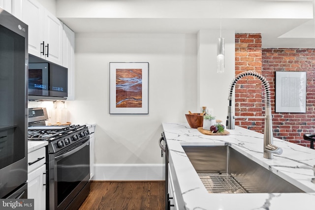 kitchen with light stone countertops, a sink, dark wood-type flooring, white cabinets, and appliances with stainless steel finishes