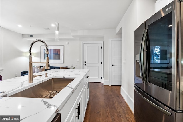 kitchen with dark wood-style floors, light stone countertops, a sink, stainless steel refrigerator with ice dispenser, and white cabinetry