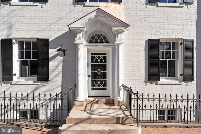 entrance to property featuring fence and brick siding