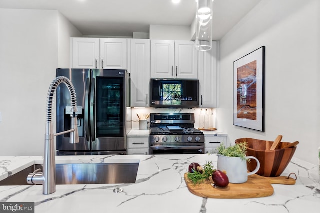 kitchen featuring white cabinets, stainless steel appliances, and light stone countertops