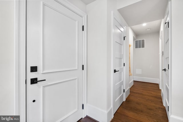 hall featuring visible vents, dark wood-type flooring, and baseboards