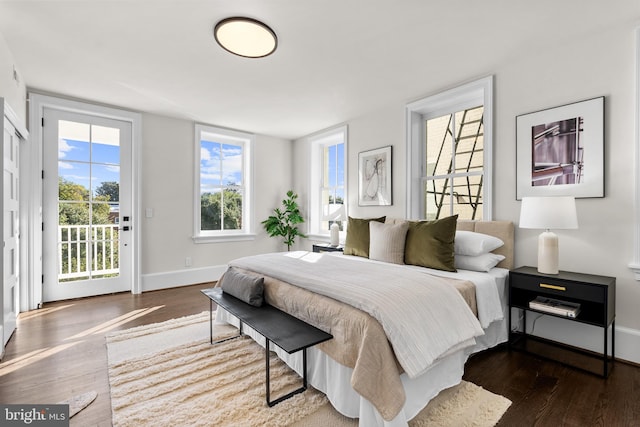 bedroom featuring access to exterior, baseboards, and wood finished floors