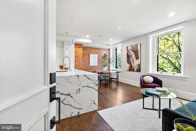 living room featuring dark wood-style floors, recessed lighting, brick wall, and baseboards