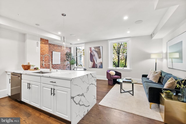 kitchen featuring dark wood-style floors, light stone countertops, a sink, stainless steel dishwasher, and open floor plan