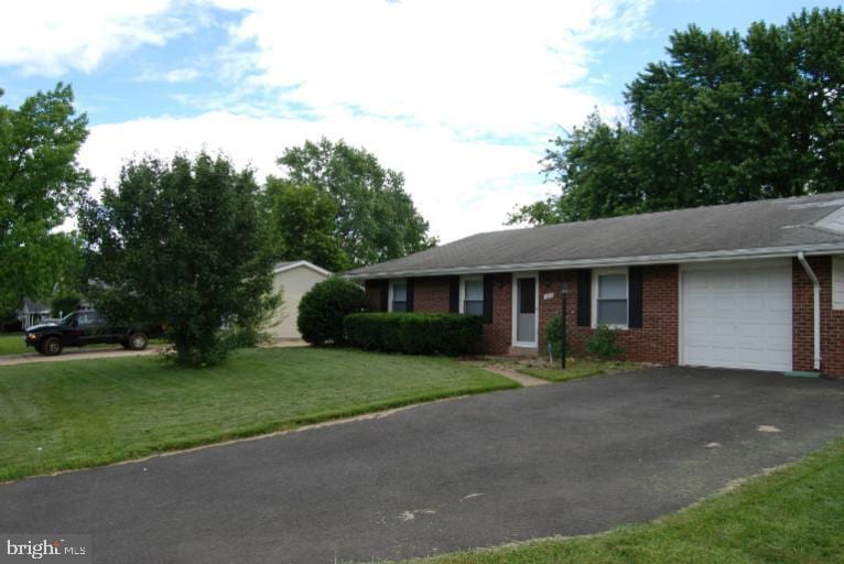 single story home with a garage, a front yard, brick siding, and driveway