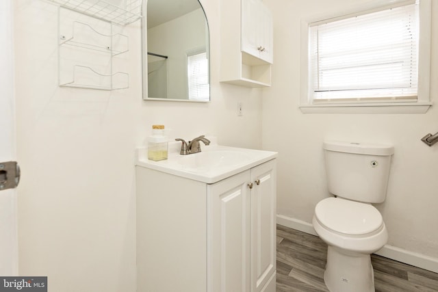 bathroom with baseboards, vanity, toilet, and wood finished floors