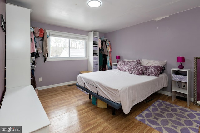 bedroom with wood finished floors, visible vents, and baseboards