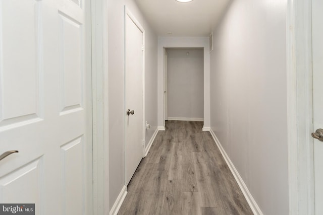 hallway featuring light wood finished floors, visible vents, and baseboards