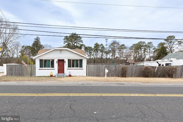 bungalow-style house featuring a chimney, uncovered parking, and fence