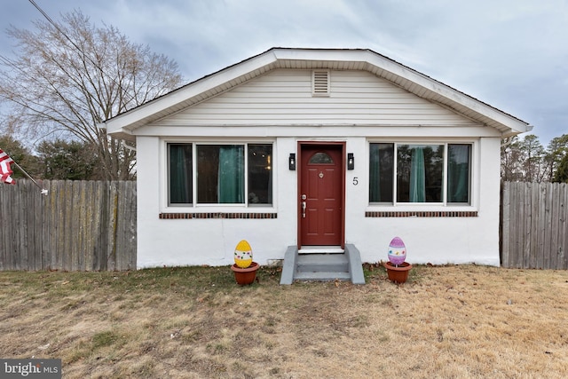 bungalow with fence and a front yard