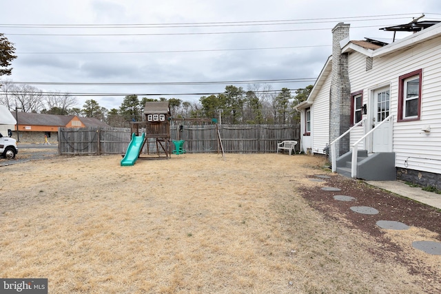 view of yard featuring entry steps, fence, and a playground