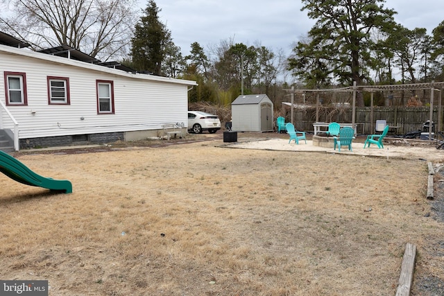 view of yard featuring an outdoor fire pit, an outbuilding, fence, a patio area, and a shed