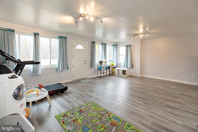 interior space featuring rail lighting, baseboards, and wood finished floors