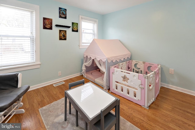 rec room with light wood-style flooring, visible vents, and baseboards