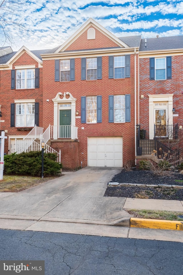 multi unit property with an attached garage, concrete driveway, and brick siding