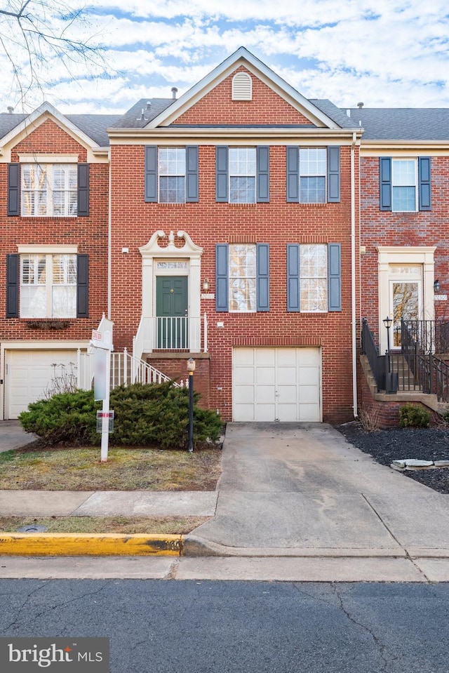 view of property with a garage, driveway, and brick siding