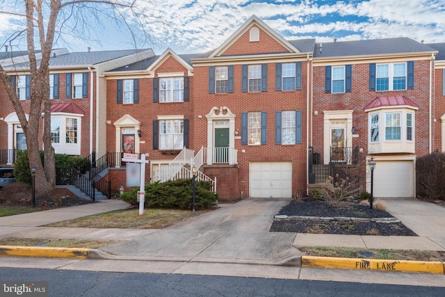 multi unit property featuring driveway, a garage, and brick siding