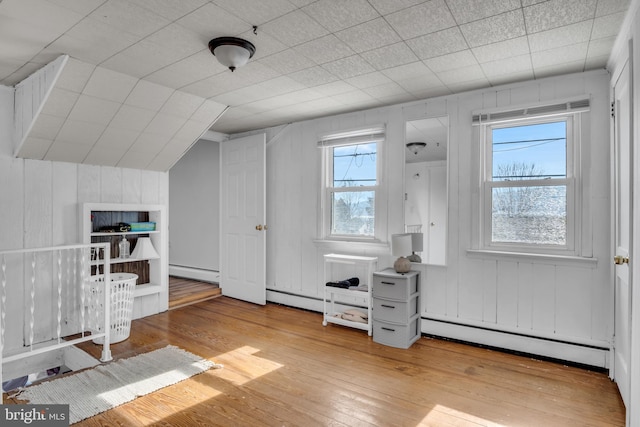 additional living space with a baseboard radiator, lofted ceiling, and hardwood / wood-style flooring