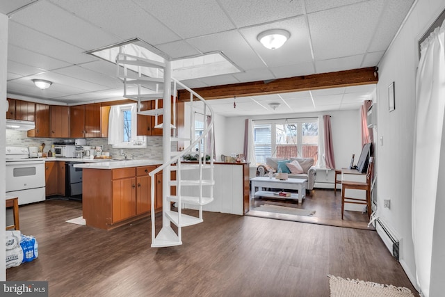 kitchen featuring a baseboard radiator, under cabinet range hood, a peninsula, white appliances, and open floor plan