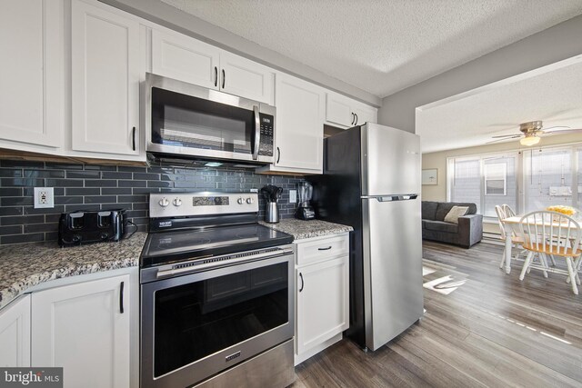 5909 Ocean Blvd, Long Beach Township, NJ 08008 - kitchen with tasteful backsplash, dark wood-type flooring, appliances with stainless steel finishes, white cabinets, and a textured ceiling