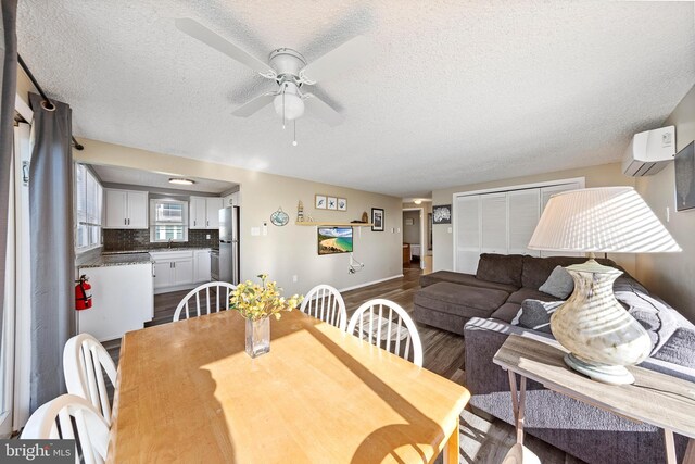 5909 Ocean Blvd, Long Beach Township, NJ 08008 - dining space with dark wood-type flooring, baseboards, an AC wall unit, a textured ceiling, and a ceiling fan