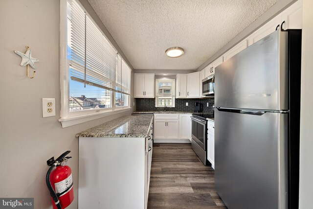 5909 Ocean Blvd, Long Beach Township, NJ 08008 - kitchen featuring backsplash, dark wood-type flooring, light stone countertops, white cabinets, and stainless steel appliances
