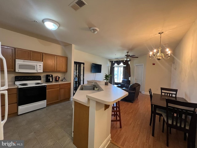 kitchen featuring white microwave, open floor plan, light countertops, a sink, and range with electric stovetop