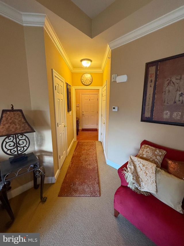 corridor featuring carpet floors, ornamental molding, and baseboards