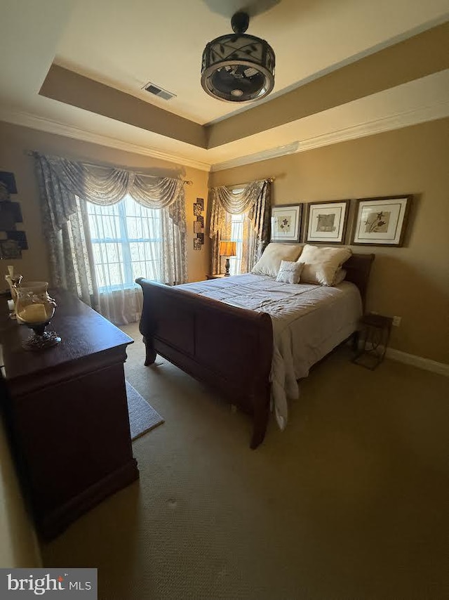 bedroom with a tray ceiling, carpet flooring, visible vents, and crown molding