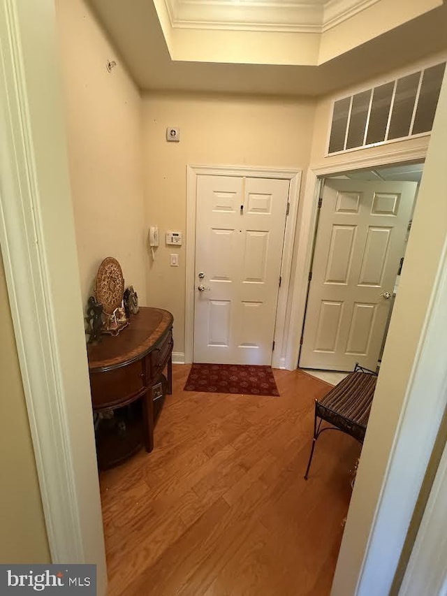 doorway with ornamental molding, wood finished floors, and visible vents