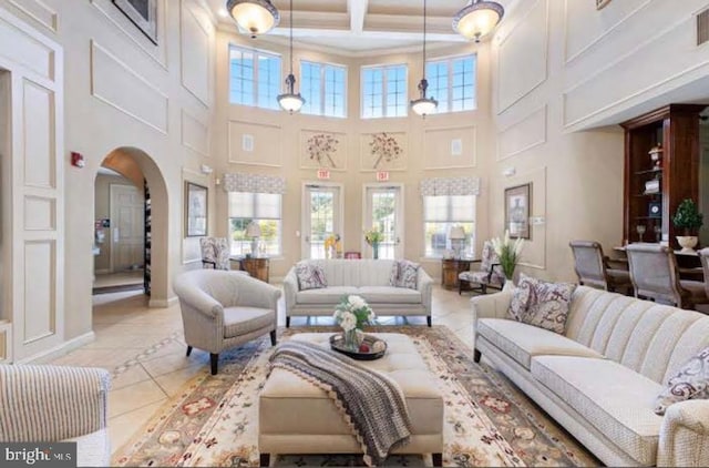 living room with arched walkways, coffered ceiling, a decorative wall, and light tile patterned floors