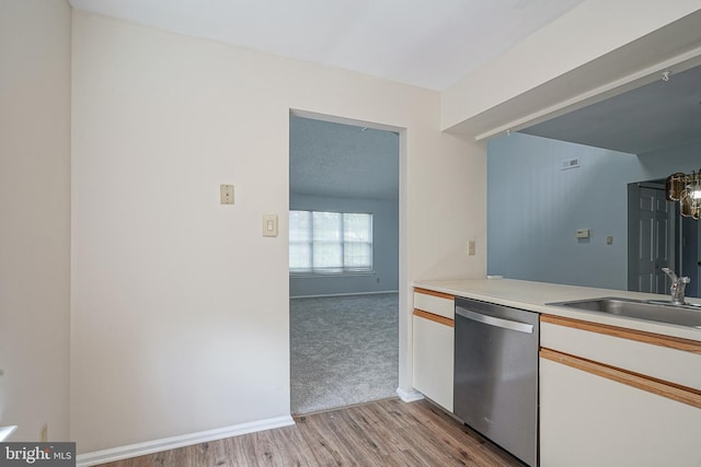 kitchen with a sink, white cabinets, light countertops, light wood-type flooring, and dishwasher