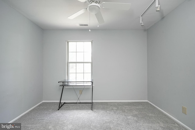 carpeted spare room with a ceiling fan, rail lighting, visible vents, and baseboards