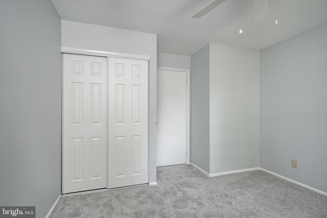 unfurnished bedroom featuring ceiling fan, a closet, baseboards, and carpet flooring