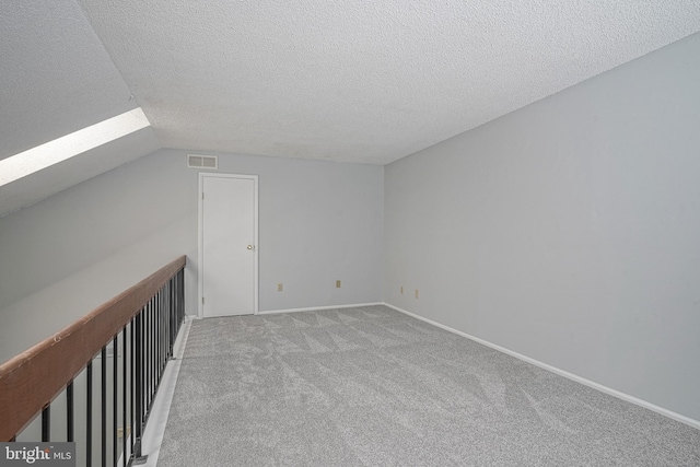 additional living space featuring a textured ceiling, baseboards, carpet flooring, and lofted ceiling