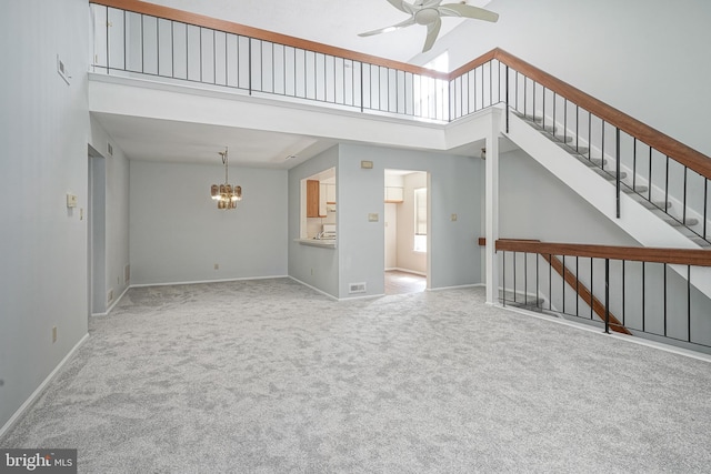 unfurnished living room with baseboards, carpet flooring, a high ceiling, and ceiling fan with notable chandelier