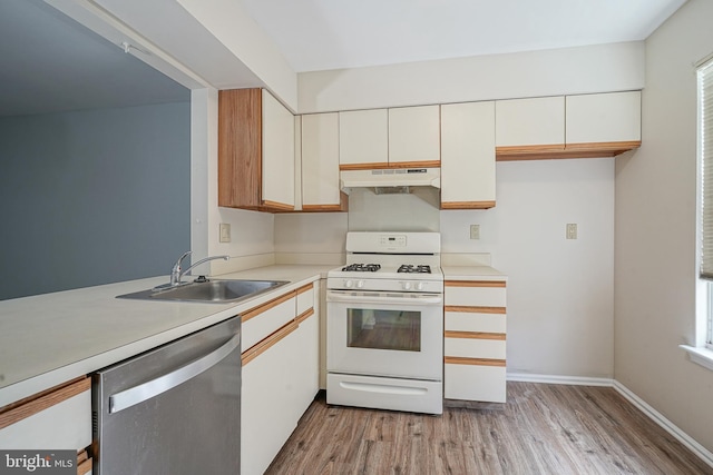 kitchen with light countertops, stainless steel dishwasher, a sink, under cabinet range hood, and white gas range oven