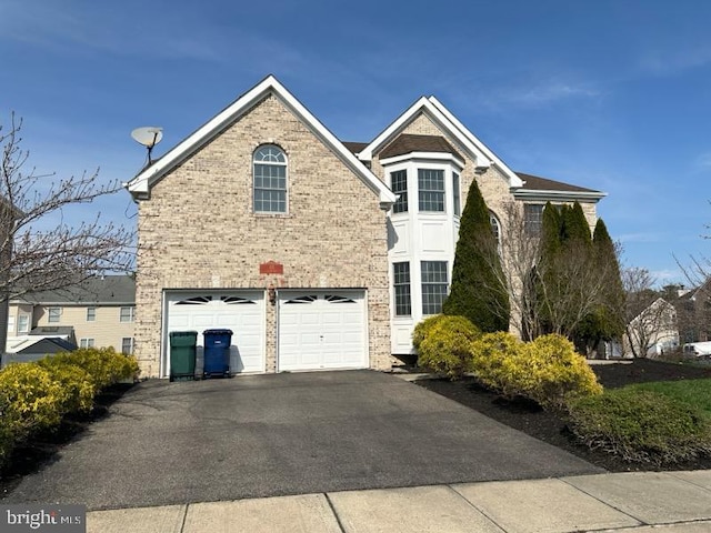 view of front facade with an attached garage, aphalt driveway, and brick siding
